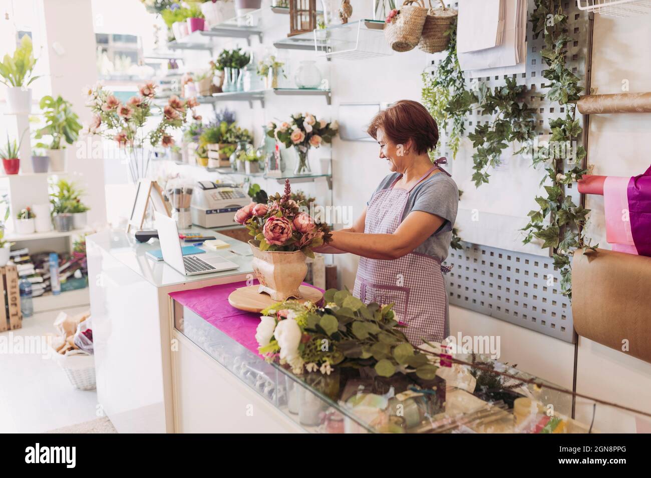 Weibliche Unternehmerin mit kurzen Haaren, die Blumen arrangiert, während sie im Geschäft arbeitet Stockfoto