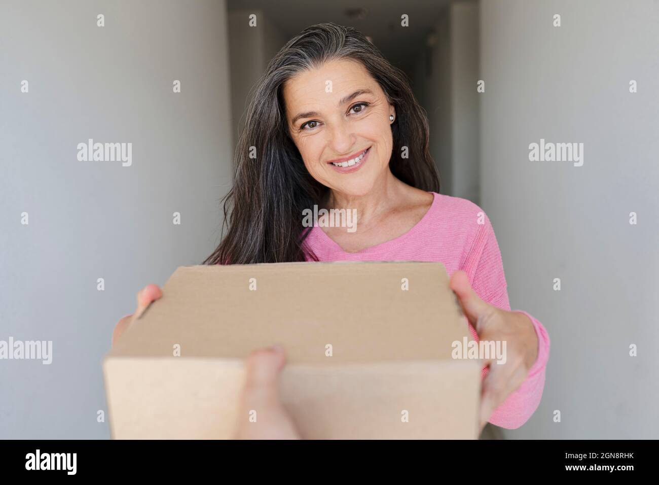 Schöne lächelnde Frau, die das Paket von der Lieferperson erhält Stockfoto