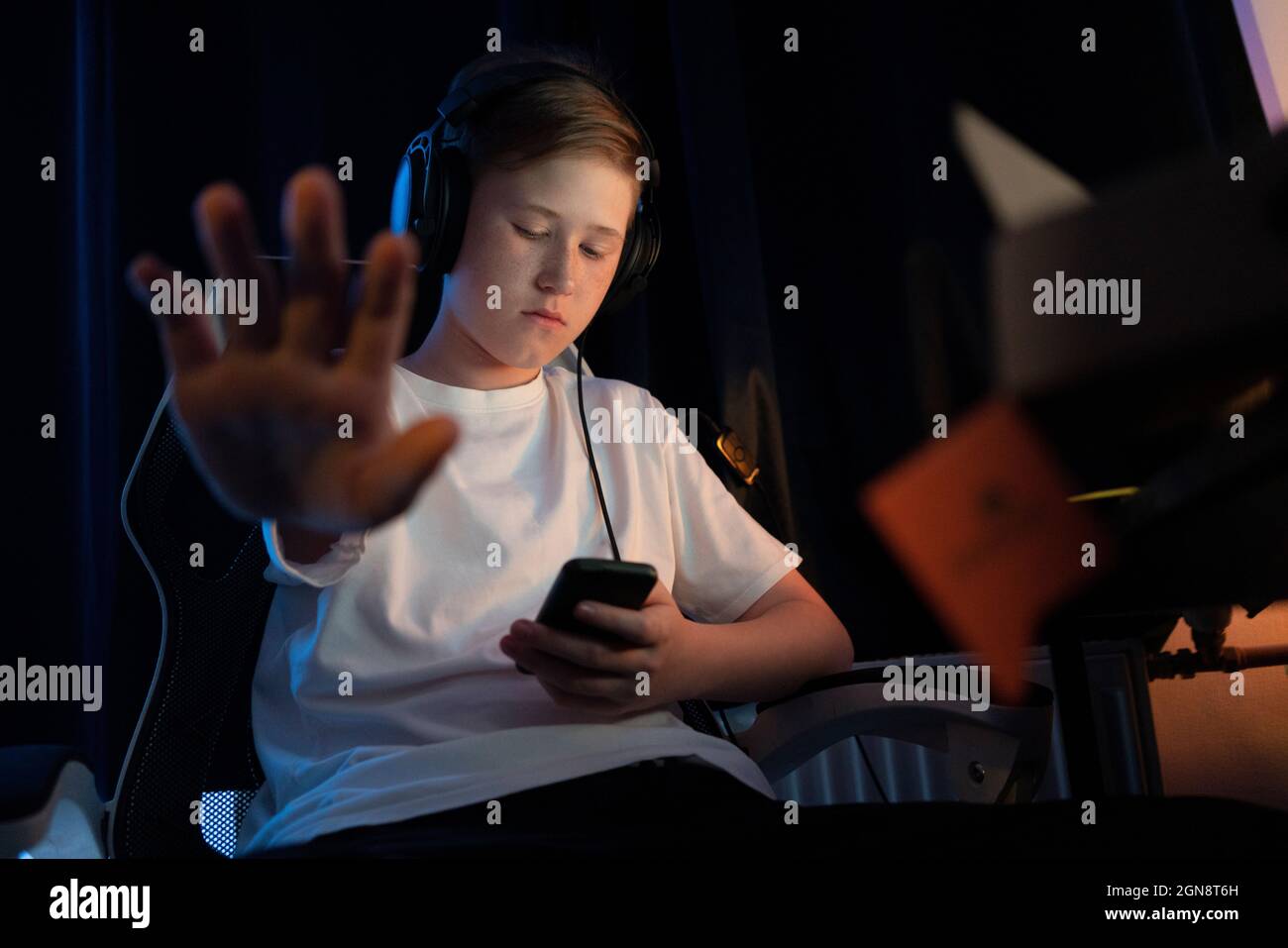 Junge zeigt Stoppschild, während er zu Hause Smartphone benutzt Stockfoto