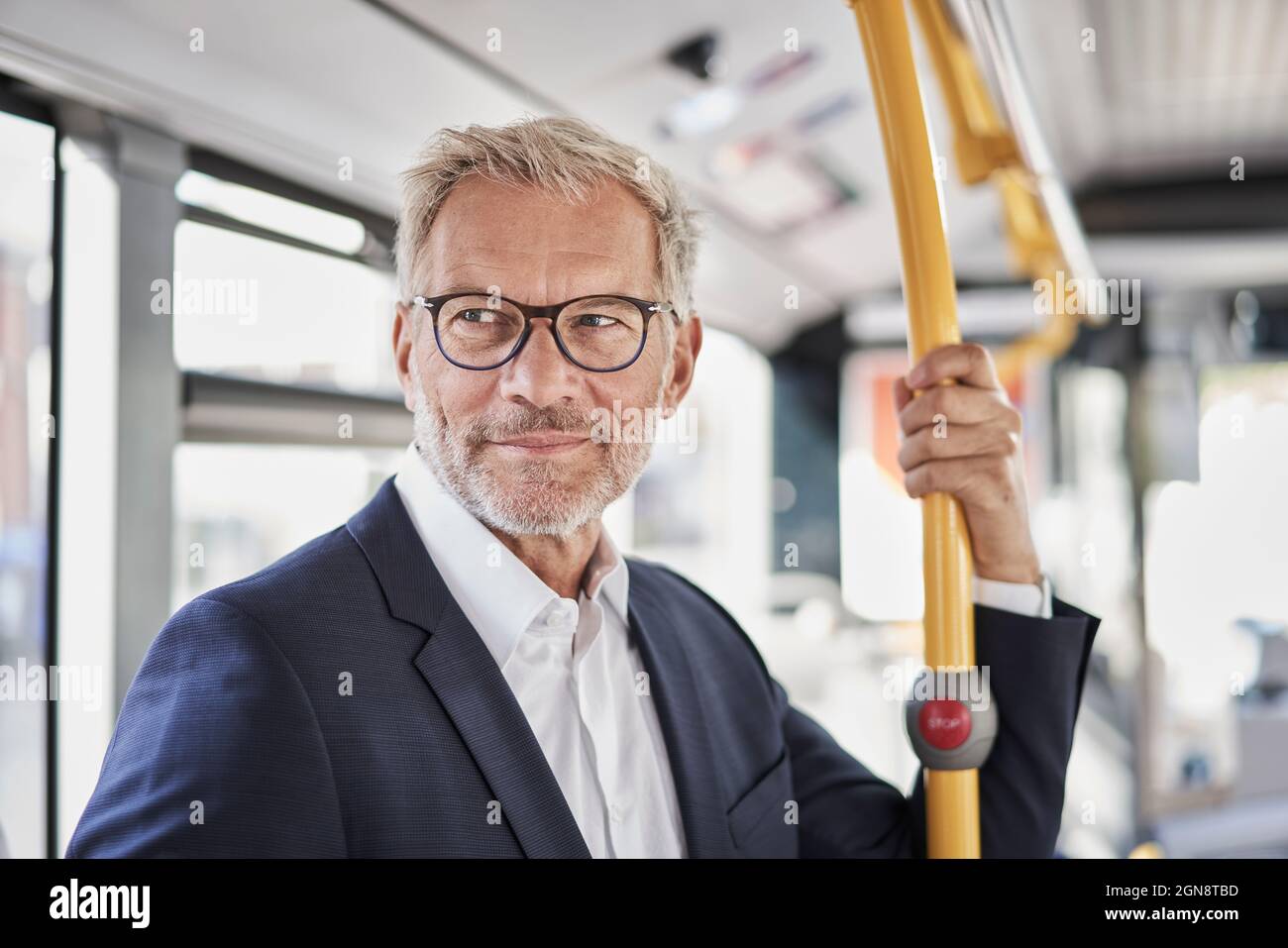 Ein älterer männlicher Profi schaut weg, während er mit dem Bus unterwegs ist Stockfoto