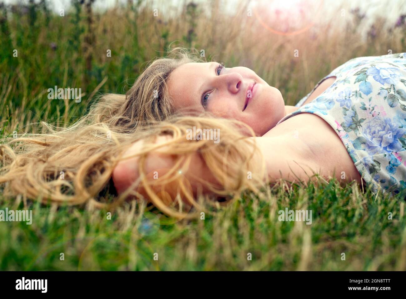 Lächelndes Mädchen Tag träumen, während auf Gras liegen Stockfoto