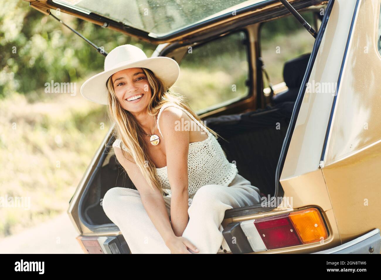 Blonde Frau mit Hut sitzt im Kofferraum Stockfoto Blonde Frau mit Hut sitzt im Kofferraum Stockfoto