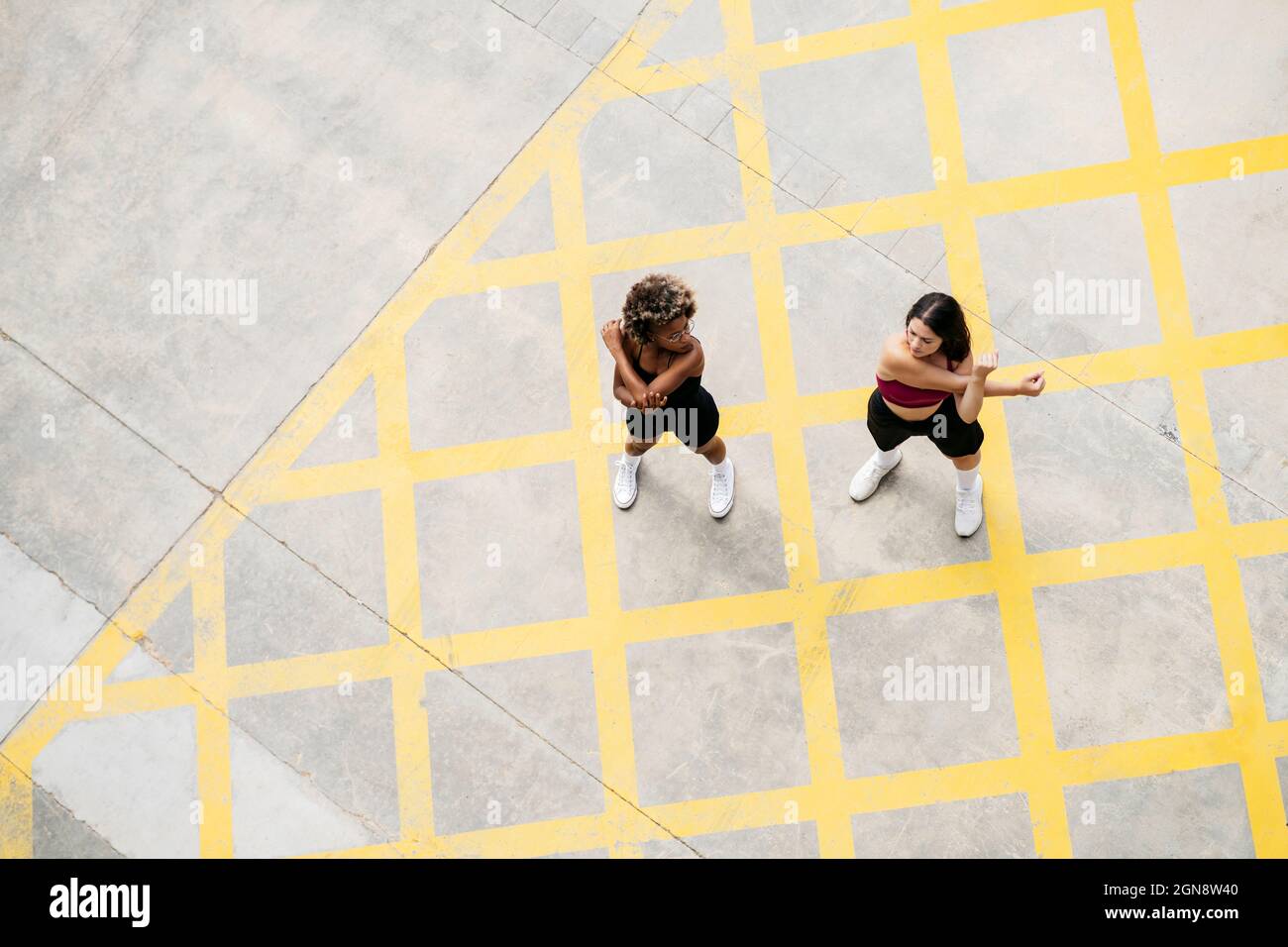 Frauen mit mittlerem Erwachsenenalter machen Aufwärmübungen auf dem Fußweg Stockfoto