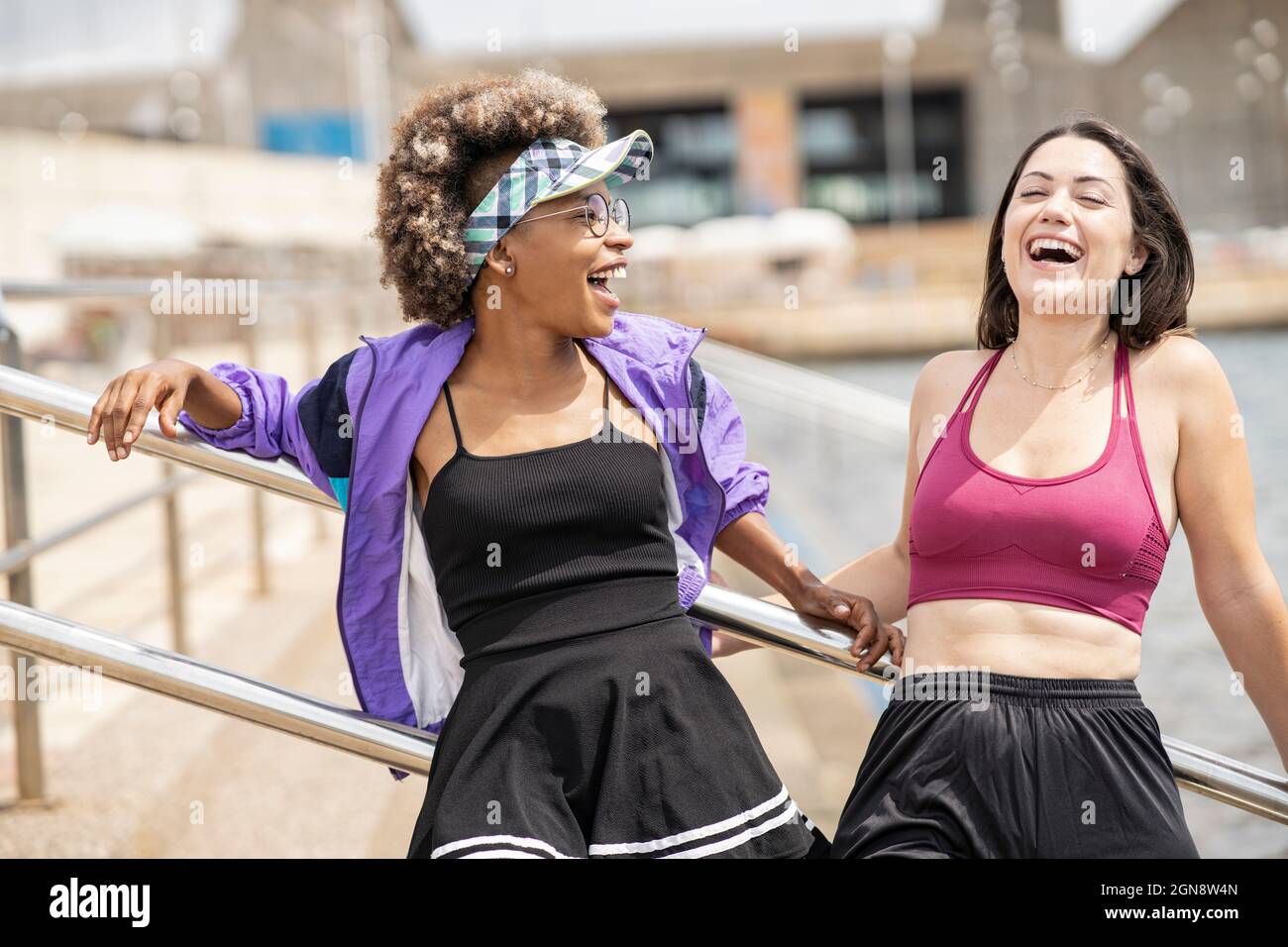 Frauen mittleren Erwachsenen, die vor dem Geländer stehen und lachen Stockfoto