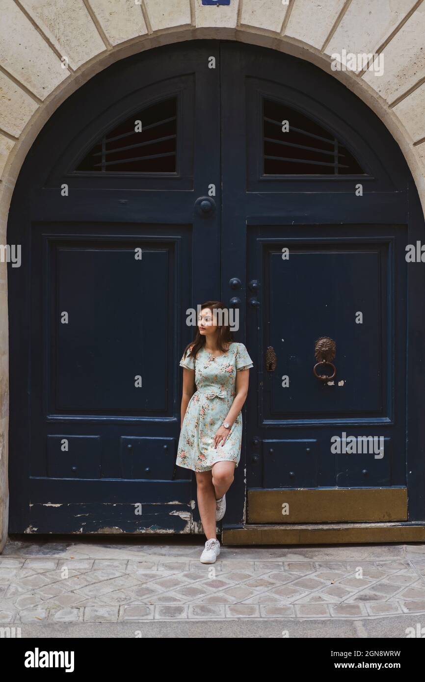 Junge Frau schaut weg, während sie vor der Tür steht Stockfoto