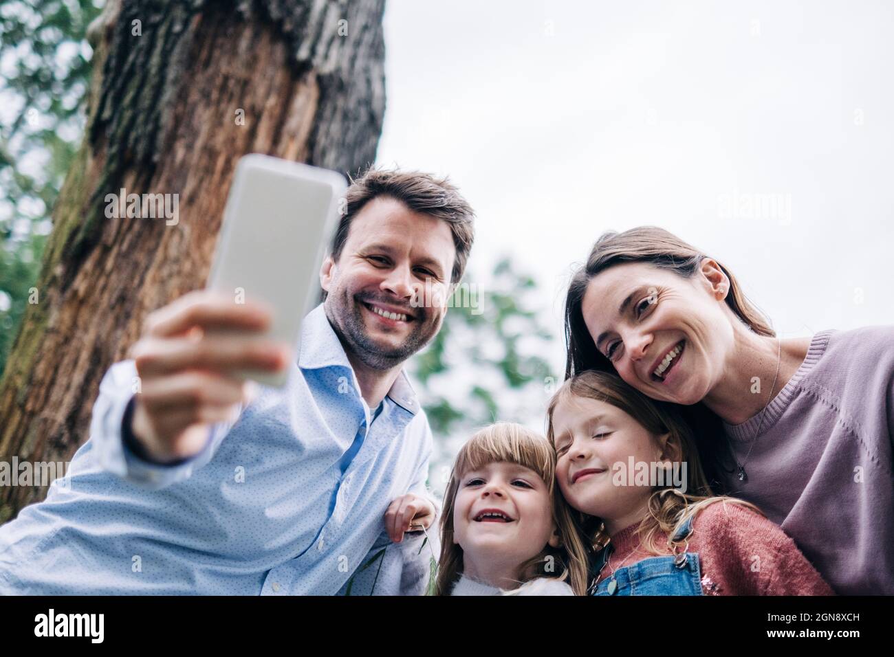 Lächelnder Vater nimmt Selfie mit der Familie über das Mobiltelefon Stockfoto