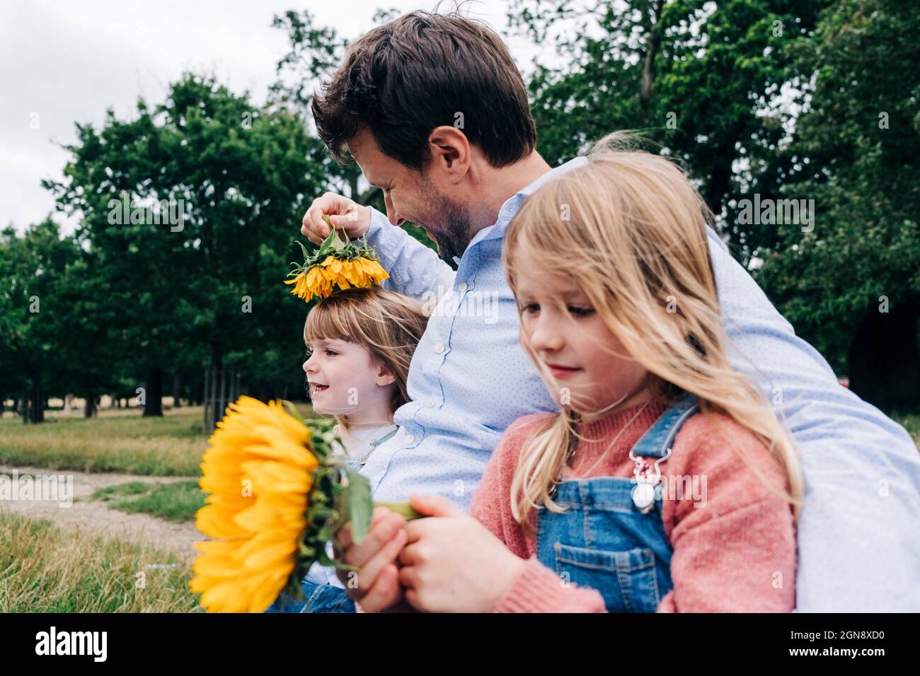 Mann mit Sonnenblume spielt mit Mädchen im Urlaub Stockfoto