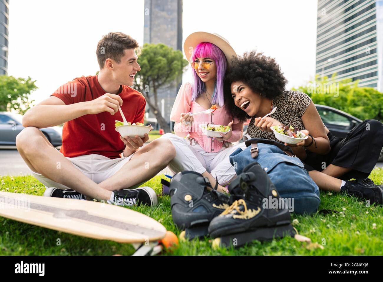 Fröhliche junge multiethnische Freunde essen Salat im Park Stockfoto
