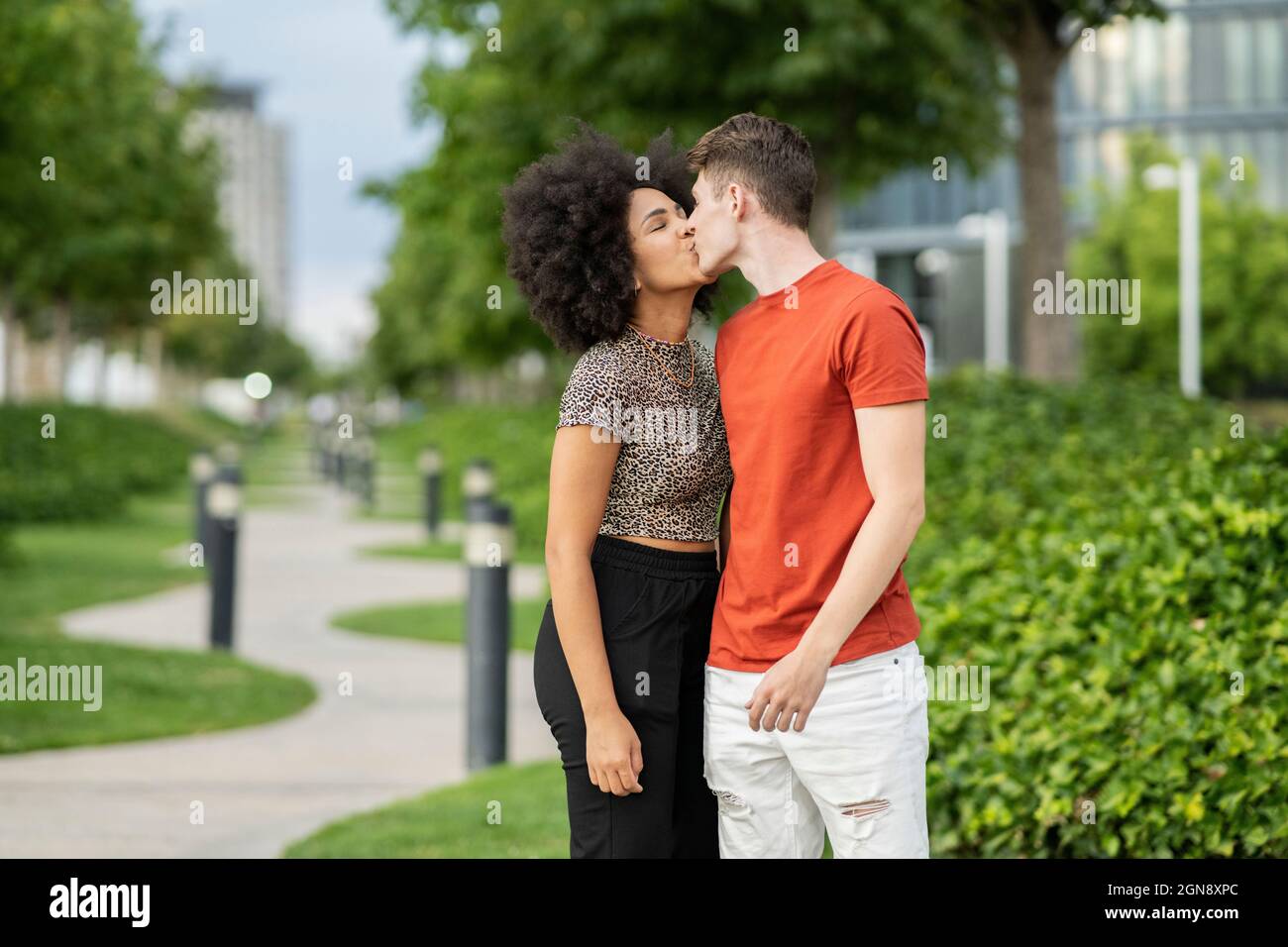 Multiethnisches Paar, das sich im Park küsst Stockfoto