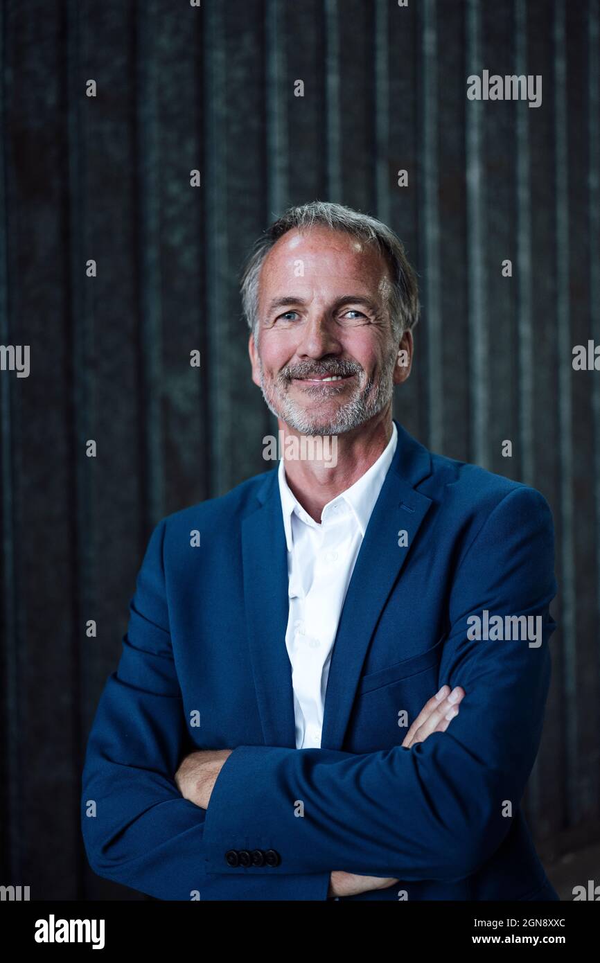 Leitender, männlicher Geschäftsexperte mit gekreuzten Armen in der Metallindustrie Stockfoto