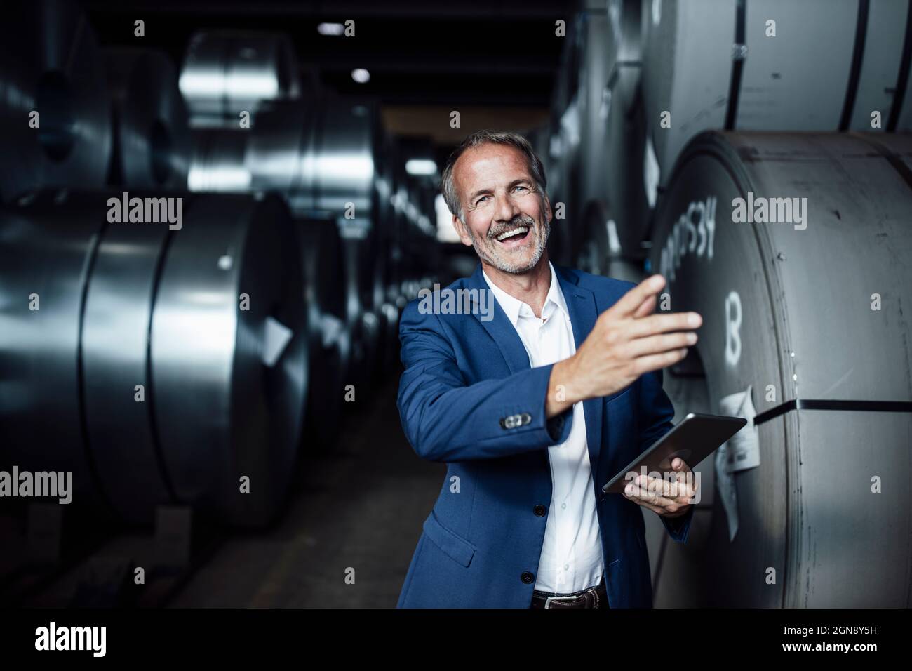 Fröhlicher Geschäftsmann mit digitalem Tablet, der im Lager steht Stockfoto