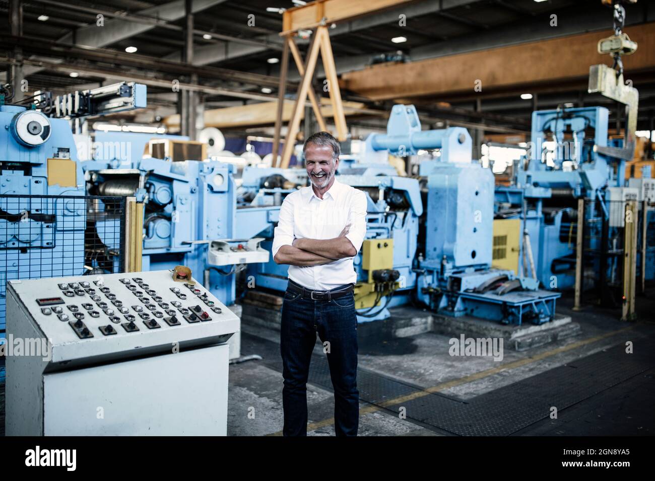 Fröhlicher Geschäftsmann mit gekreuzten Armen bei der Herstellung von Geräten Stockfoto
