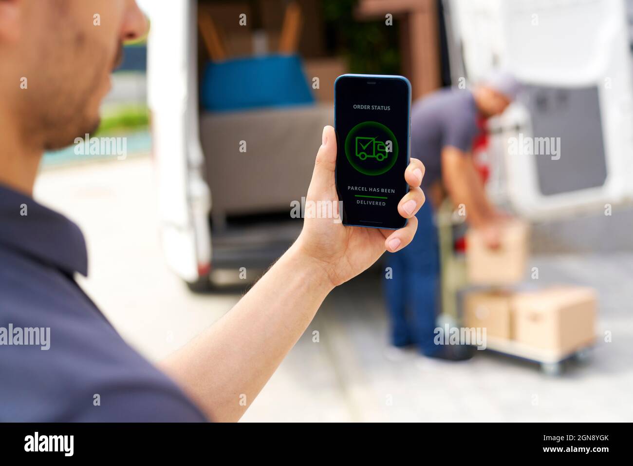 Delivery man hält Smartphone mit Handy-Anwendung Stockfoto