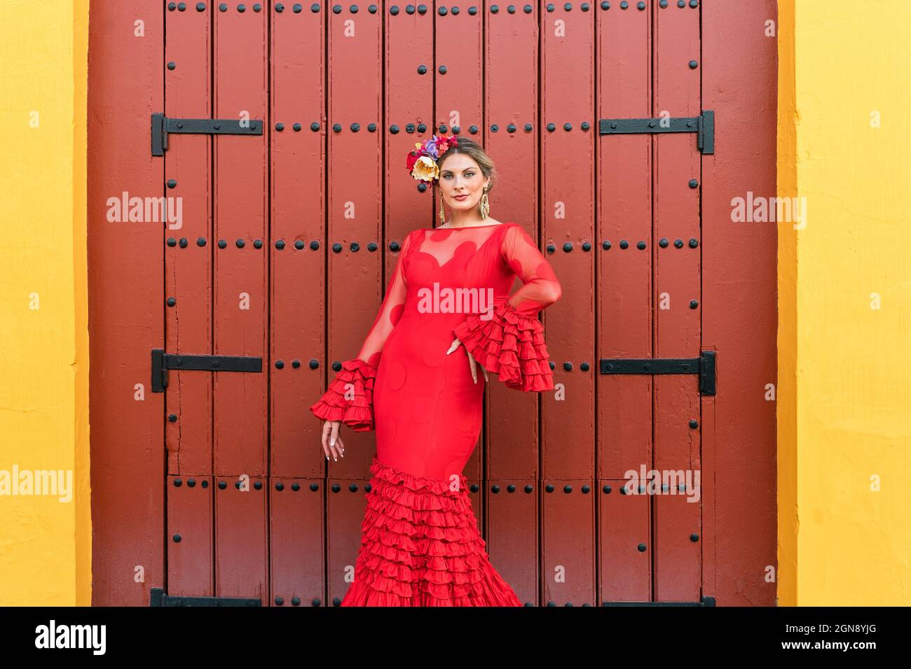 Frau im Flamenco-Kleid, die mit der Hand auf der Hüfte vor der Tür steht Stockfoto