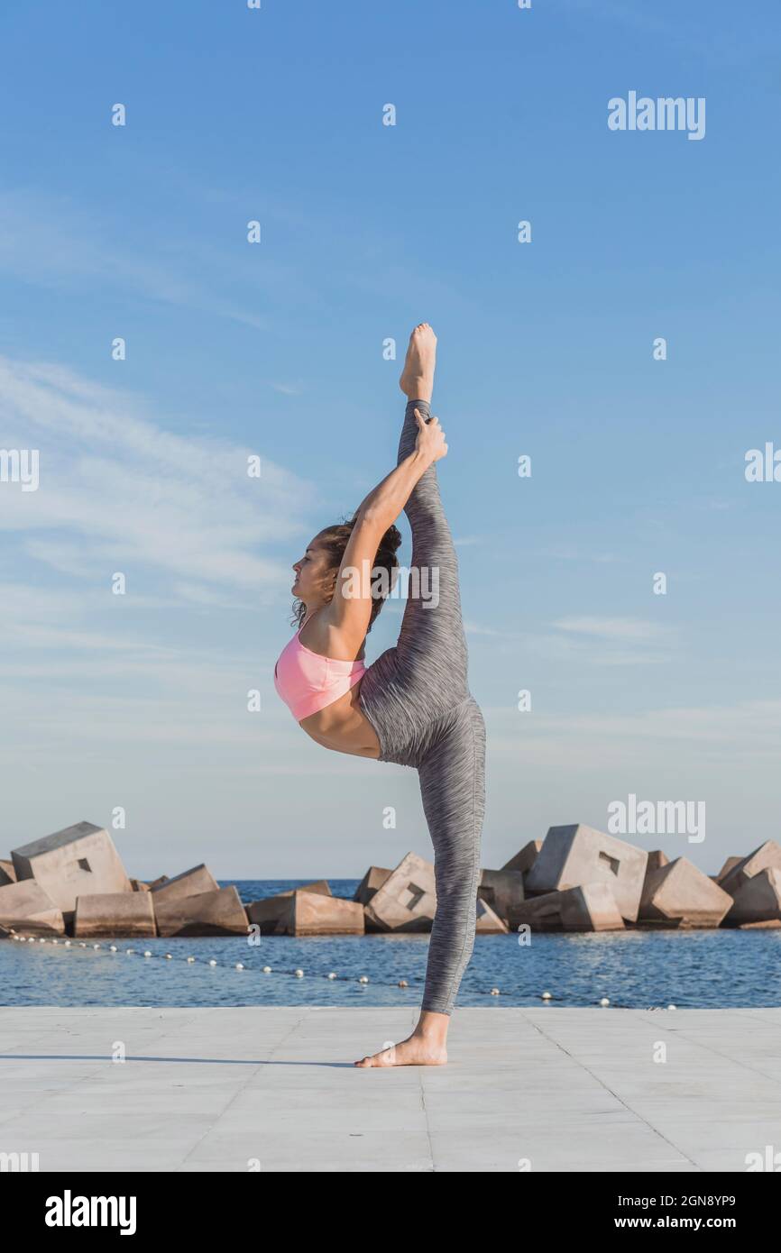 Frau, die auf einem Bein steht, während sie acroyoga auf dem Boardwalk praktiziert Stockfoto