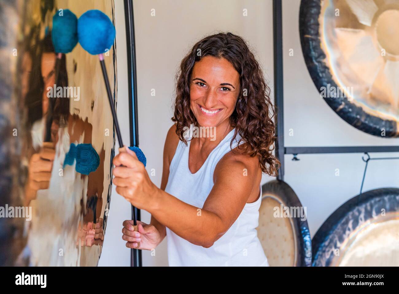 Lächelnder Klangtherapeut spielt Musikinstrument mit Schlägerchen Stockfoto