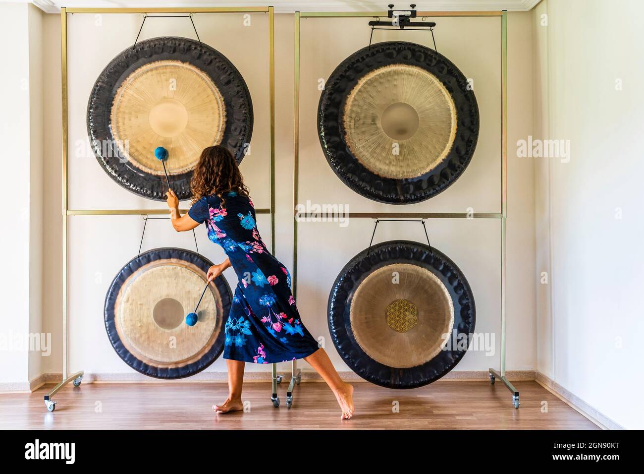 Tontherapeutin spielt Gongs mit Schlägeln im Studio Stockfoto