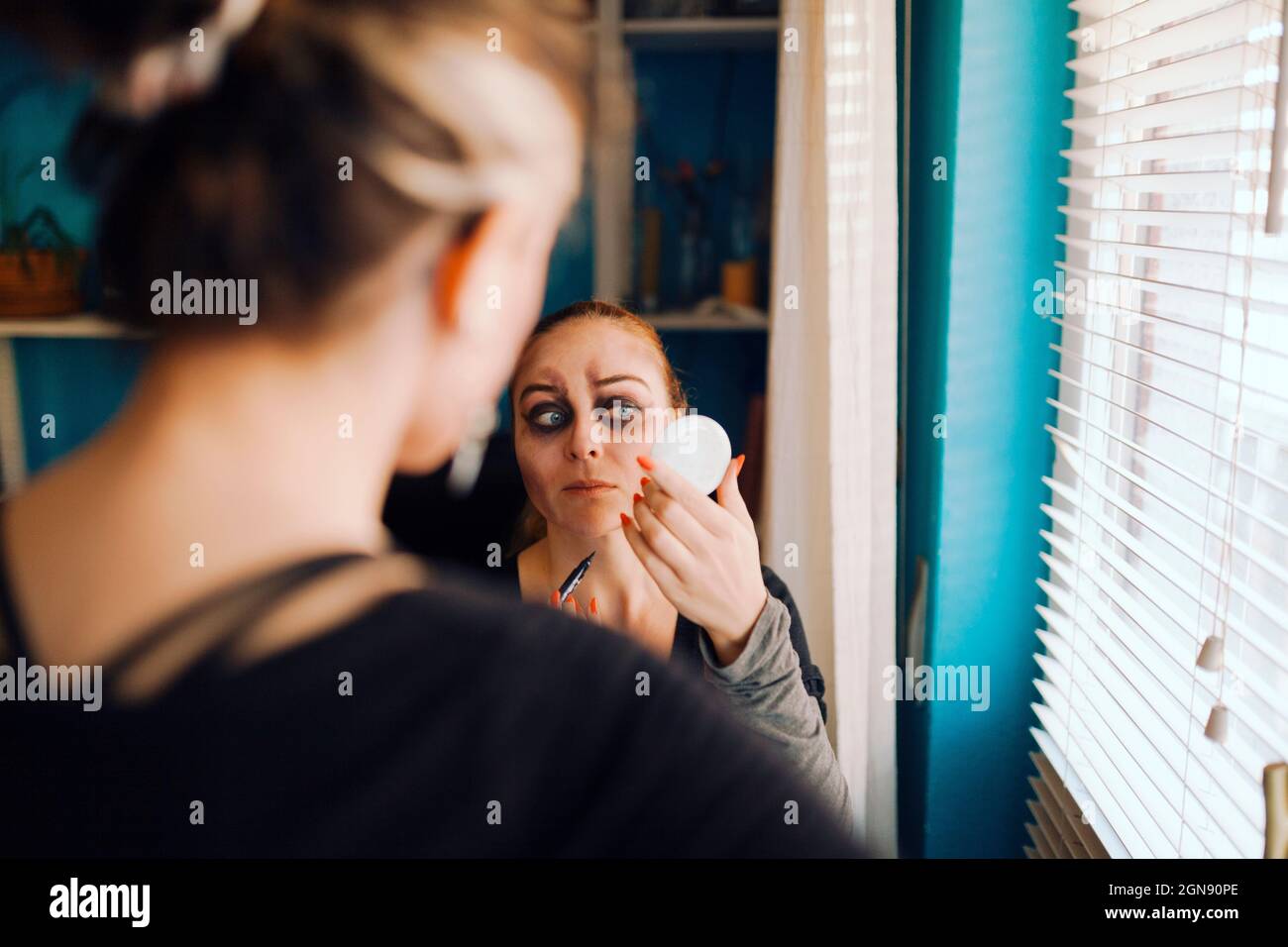 Frau, die zu Hause einen Freund ansieht, der zu Halloween Make-up macht Stockfoto