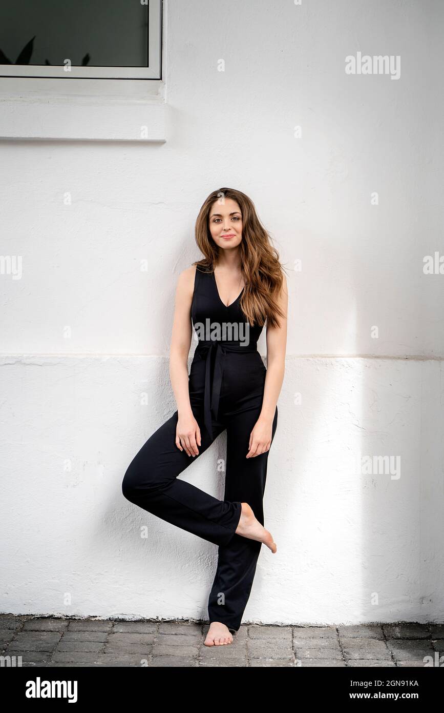 Junge Frau, die auf einem Bein vor der Wand steht Stockfoto