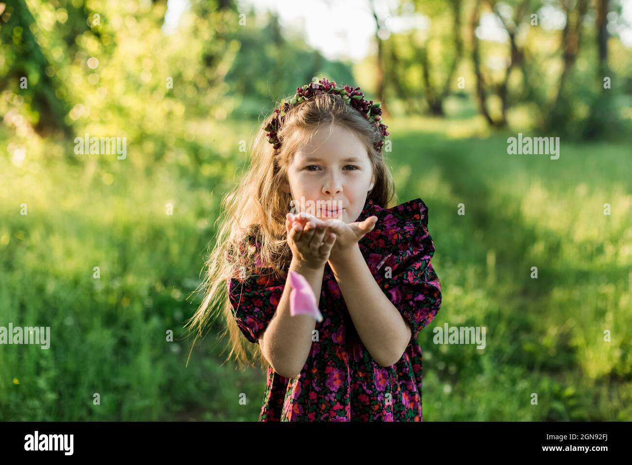 Verspielte Mädchen mit Blume Tiara weht Pfingstrose Blütenblatt Stockfoto