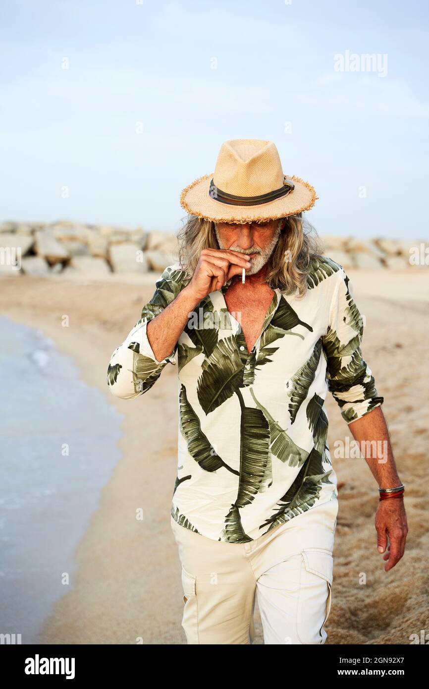 Mann raucht Zigarette, während er am Strand läuft Stockfoto