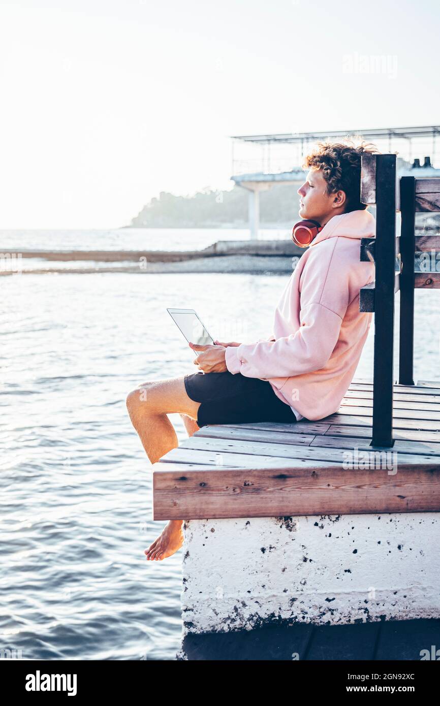 Junger Mann, der sich am Wochenende am Pier entspannt Stockfoto
