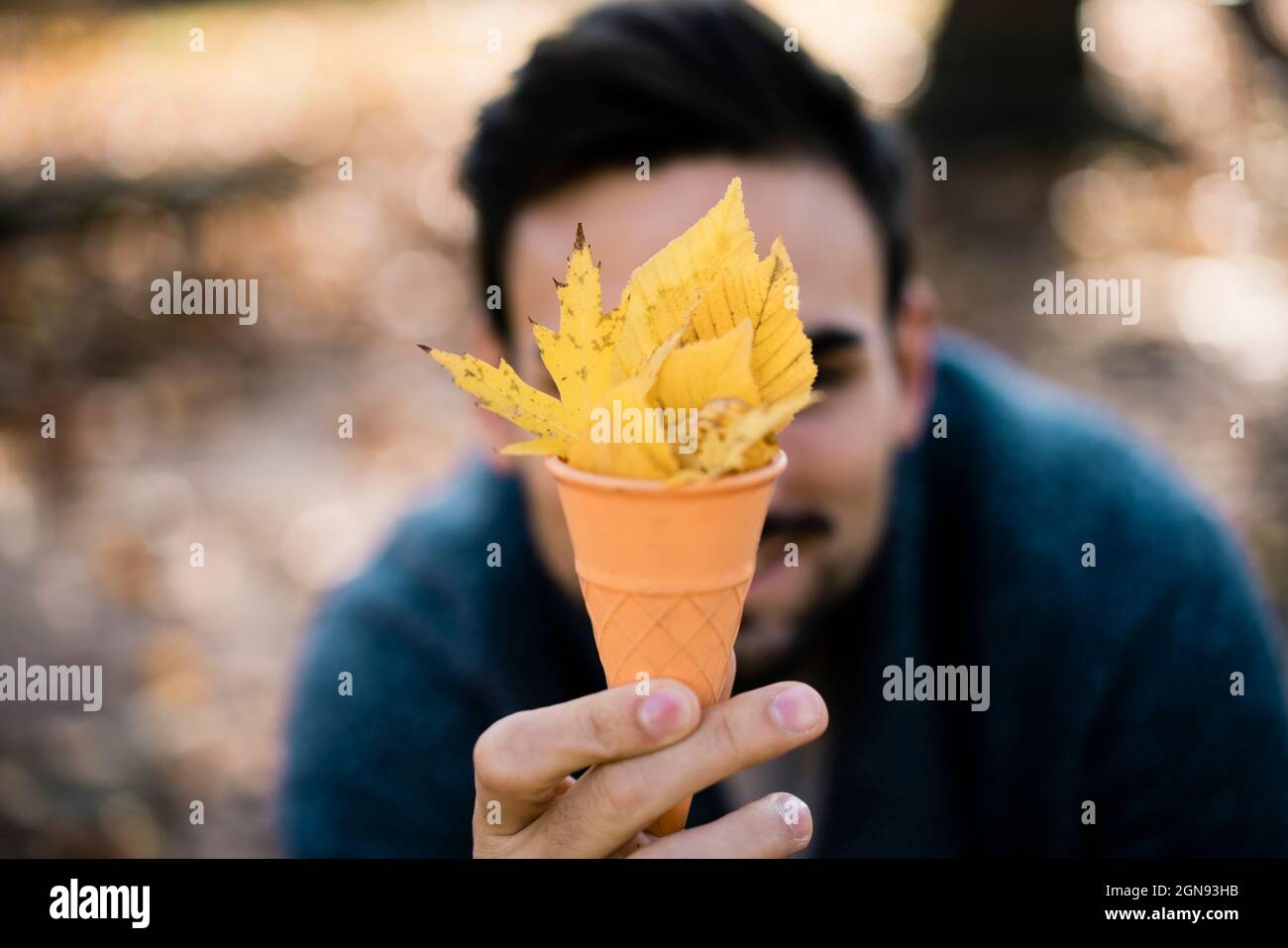 Junger Mann hält Eiskegel mit Blättern im Park Stockfoto