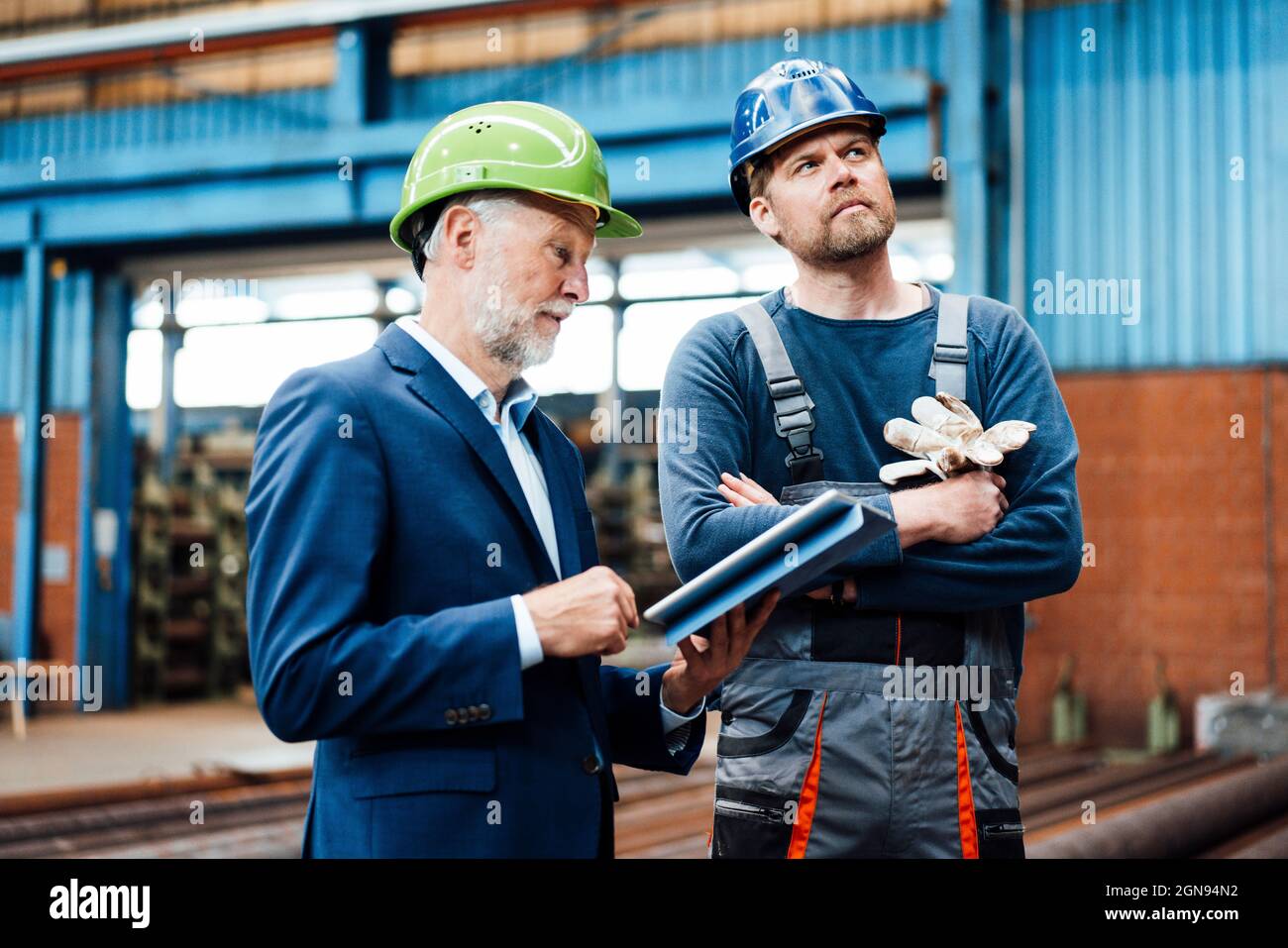 Leitender männlicher Profi, der die Ausrüstung mit einem Mitarbeiter in der Fabrik überprüft Stockfoto