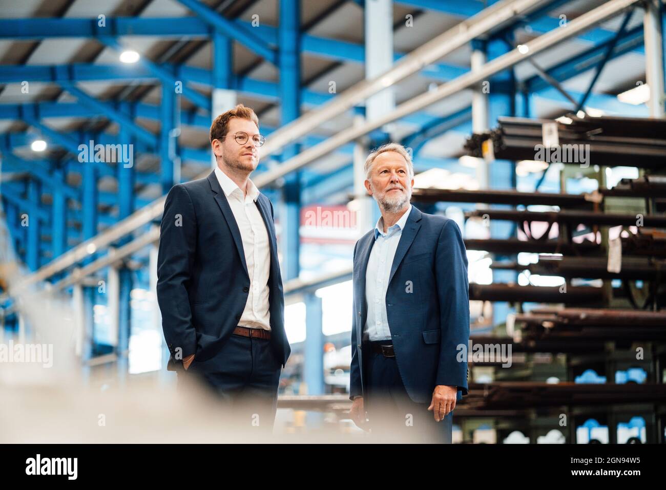 Männliche Geschäftsleute mit Händen in Taschen auf grünem Teppich in der Industrie stehen Stockfoto