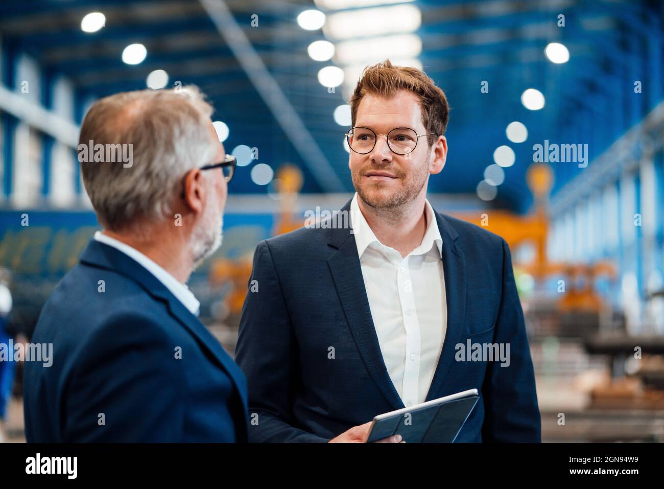 Glücklicher leitender männlicher Manager, der mit Kollegen in der Industrie diskutiert Stockfoto