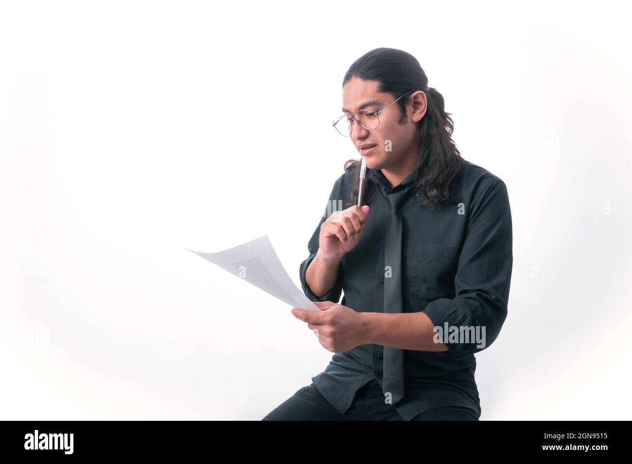 Person auf weißem Hintergrund. Er liest ein Blatt und hat einen Stift in der Hand, denkt er. In formelle Kleidung gekleidet. Leerraum. Stockfoto