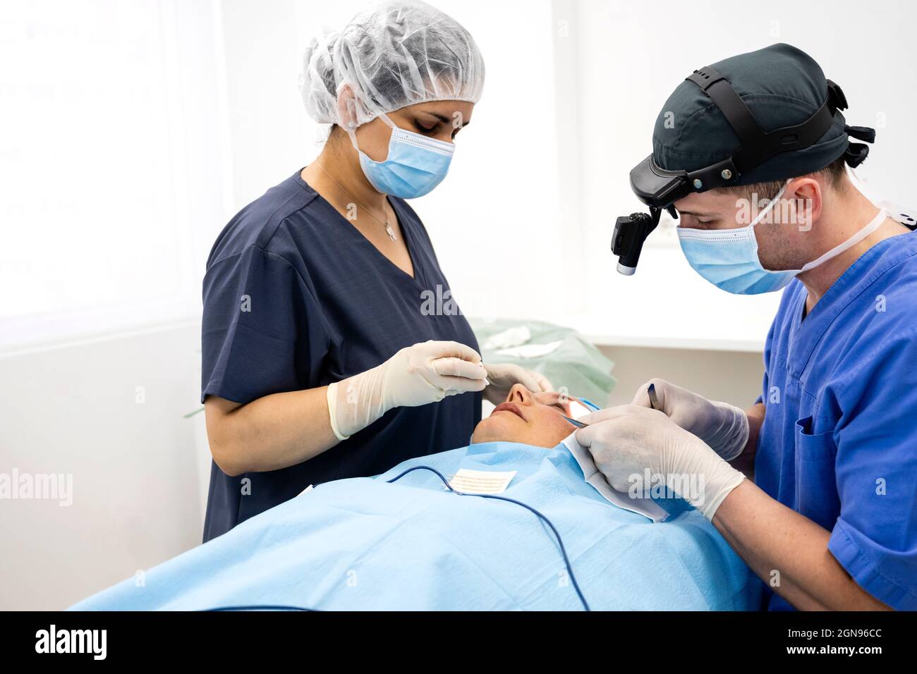 Der Chirurg näht das Augenlid nach einer plastischen Operation Stockfoto