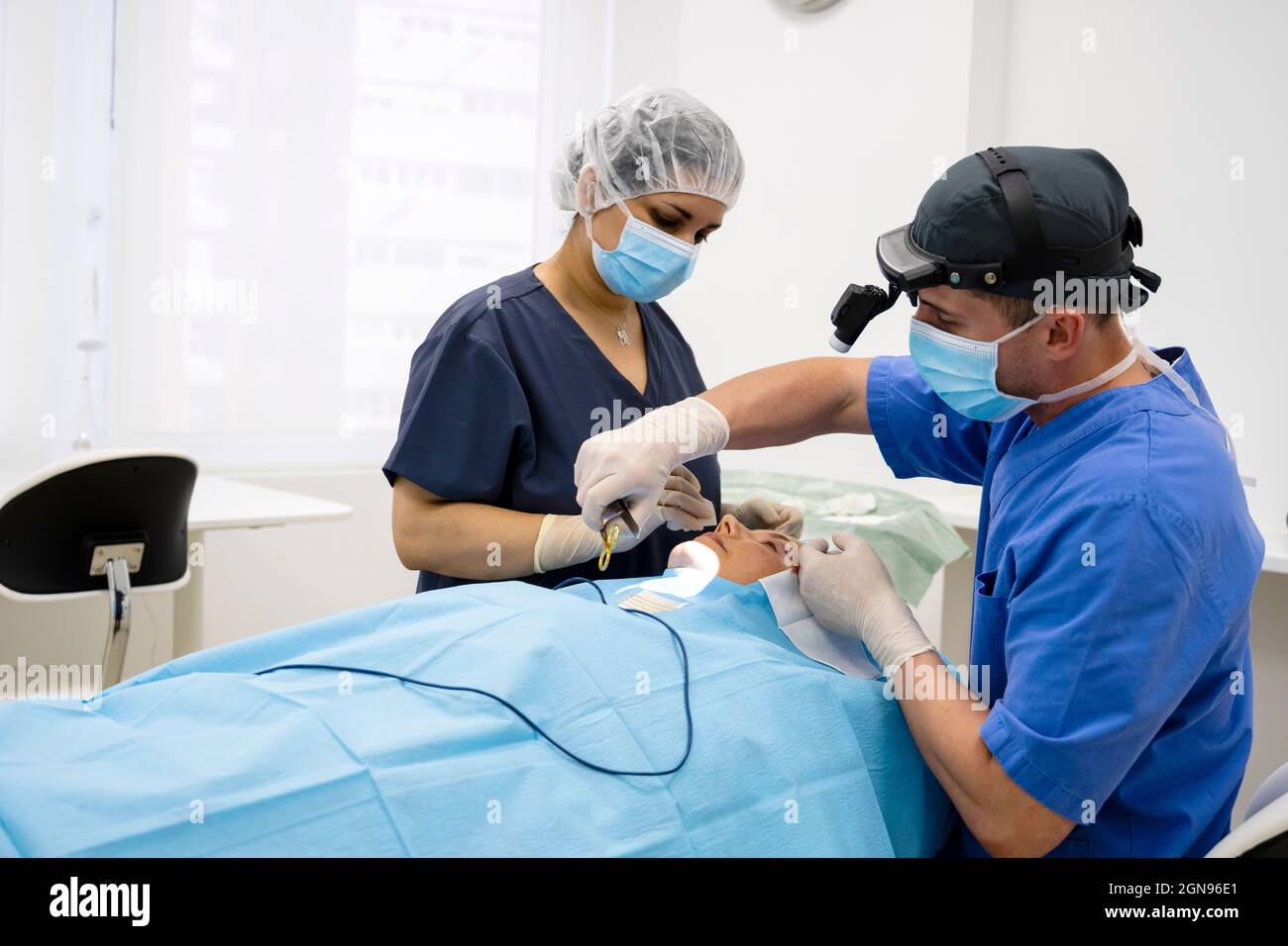 Der Chirurg näht das Augenlid nach einer plastischen Operation Stockfoto