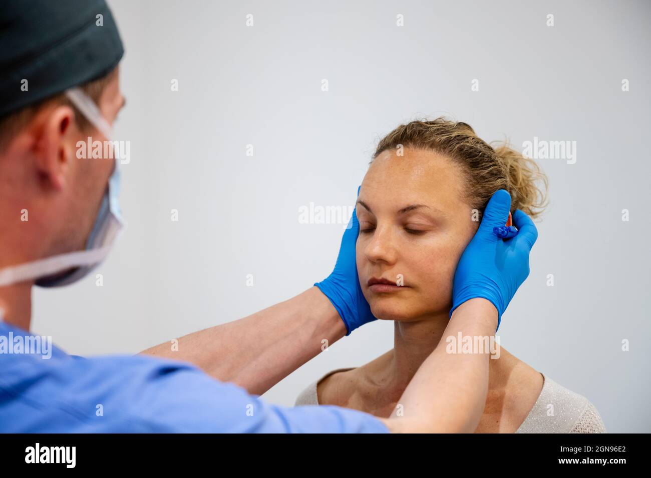 Plastischer Chirurg untersucht das Gesicht der schönen Frau Stockfoto