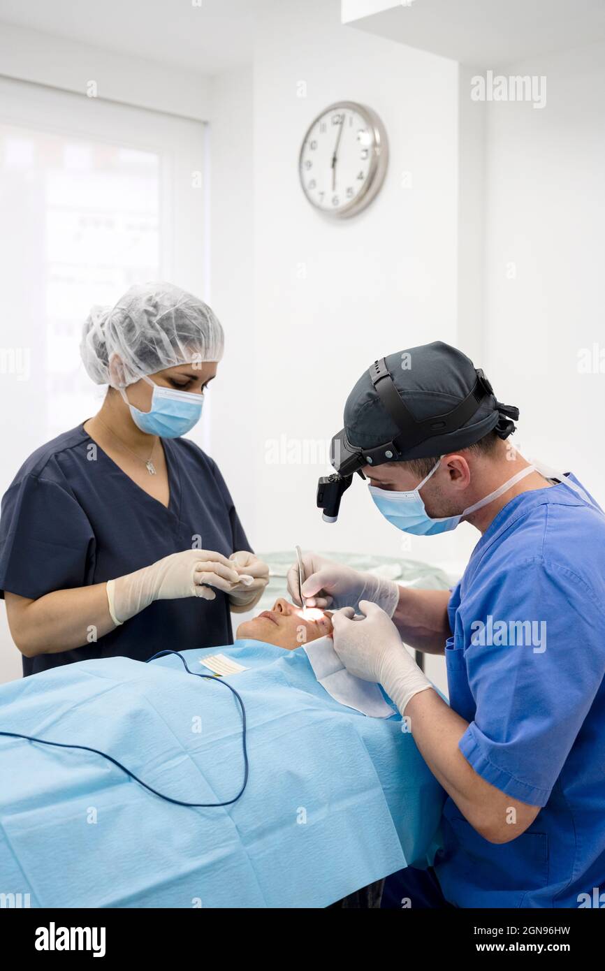Der Chirurg näht das Augenlid nach einer plastischen Operation Stockfoto