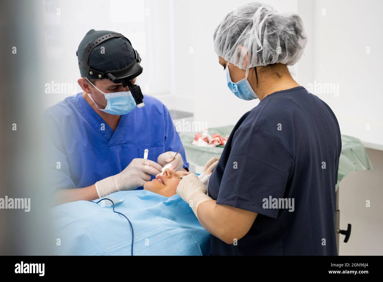 Der Chirurg näht das Augenlid nach einer plastischen Operation Stockfoto