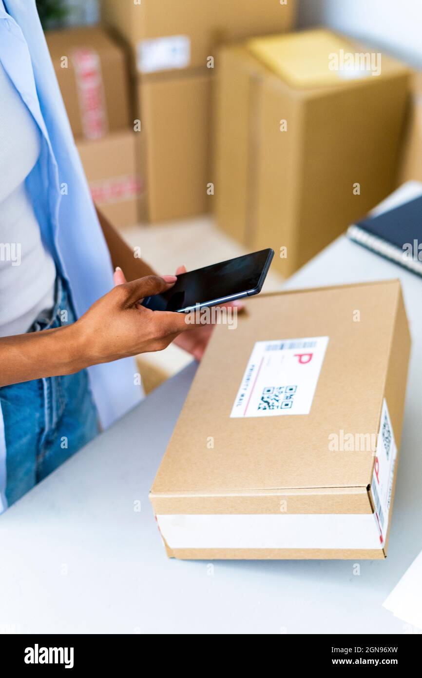 Junge Frau, die im Studio Barcode über ein Smartphone scannt Stockfoto