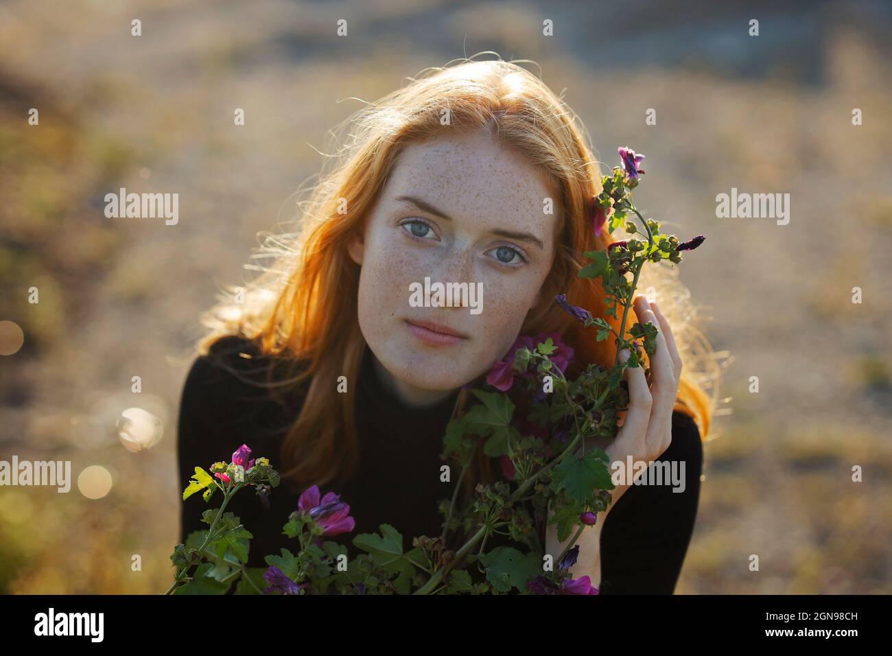 Rothaarige Frau mit blühender Pflanze Stockfoto