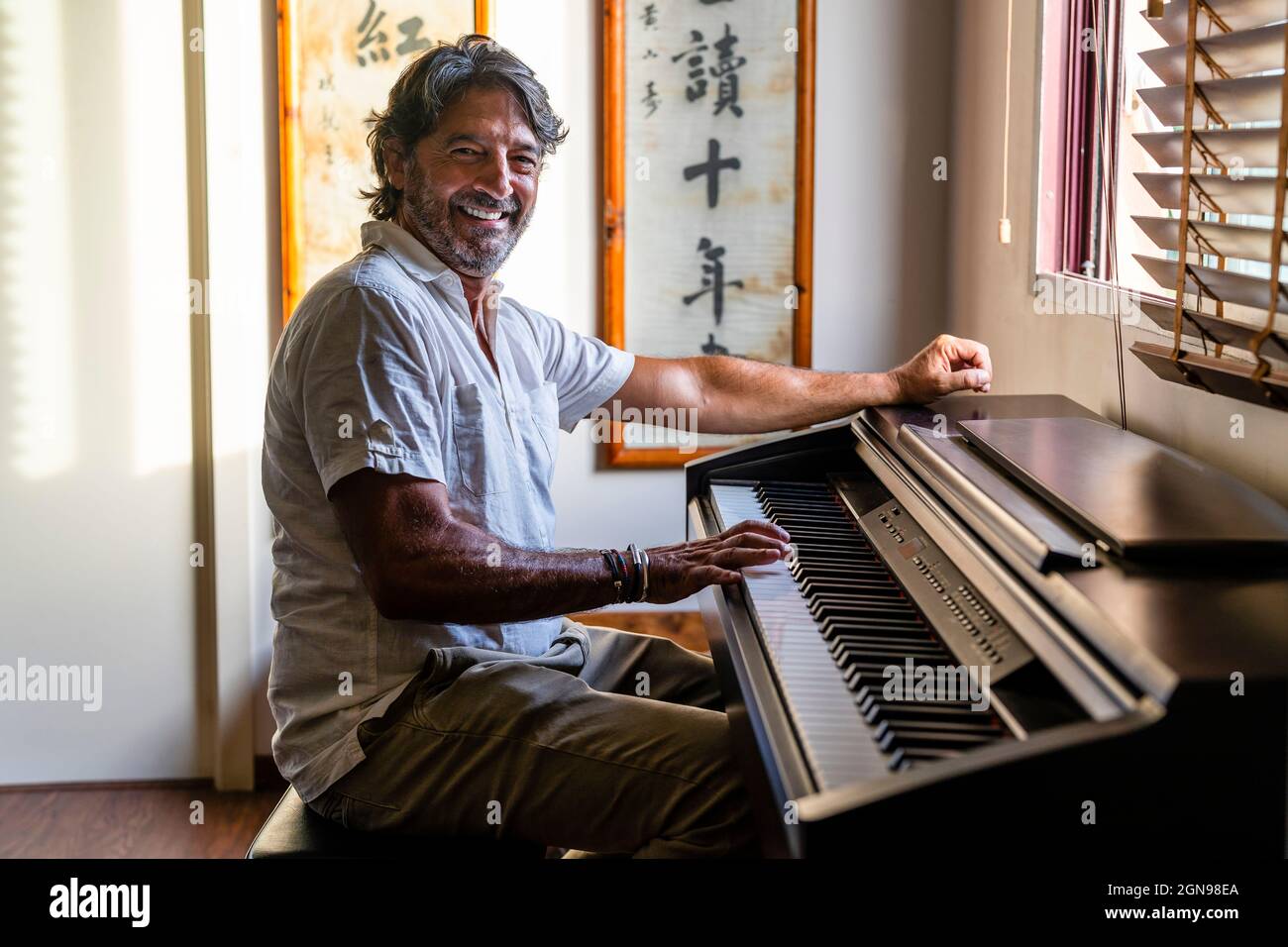 Lächelnd mann Klavier zu Hause spielen Stockfoto