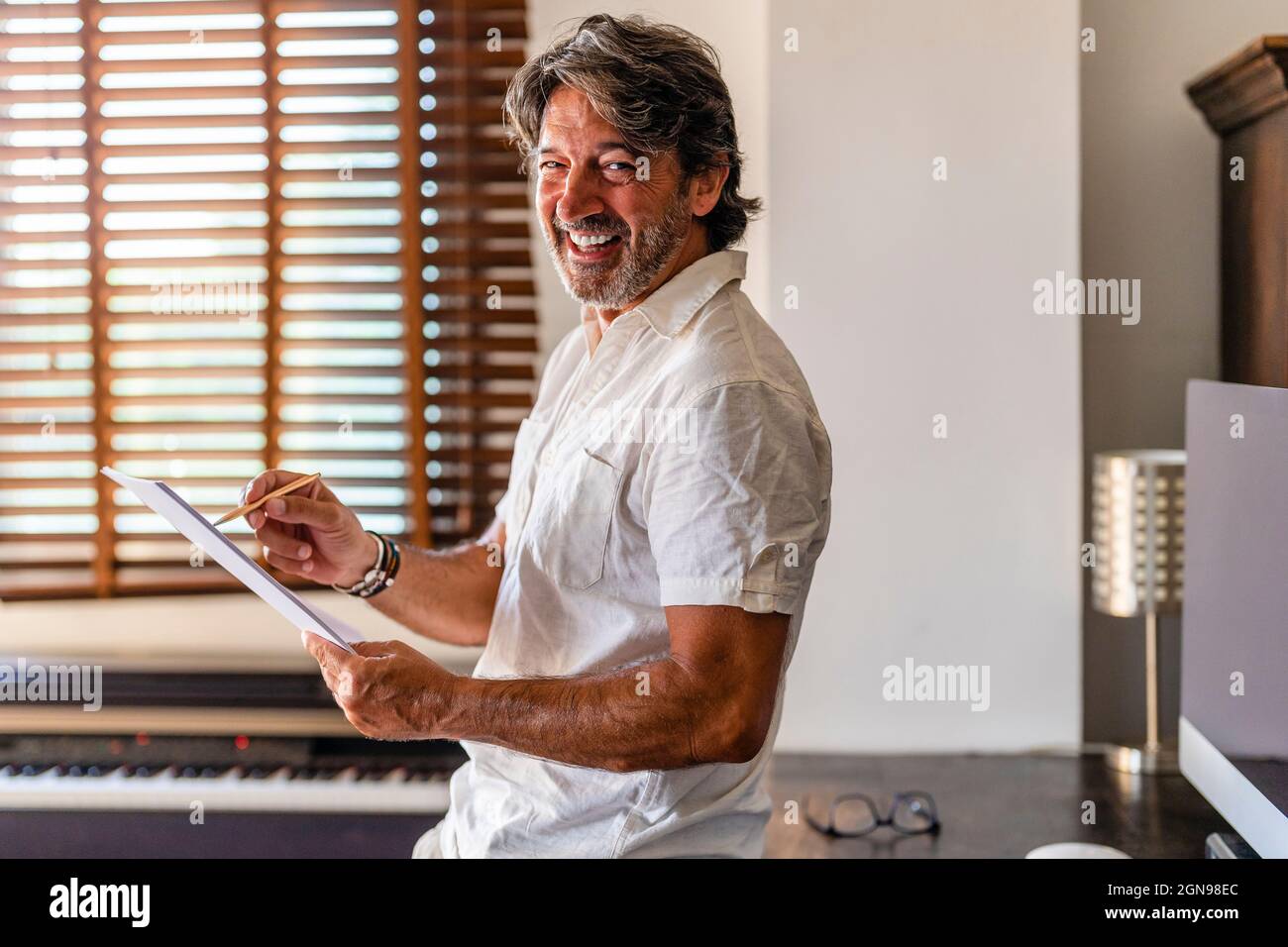 Fröhlicher Geschäftsmann mit Dokumenten, die zu Hause stehen Stockfoto