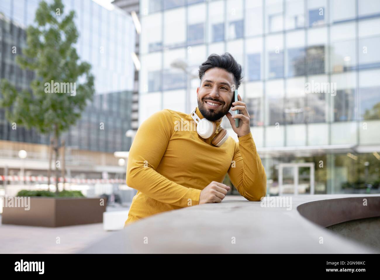 Glücklicher Mann mit Kopfhörer, der ein digitales Tablet auf der Bank verwendet Stockfoto