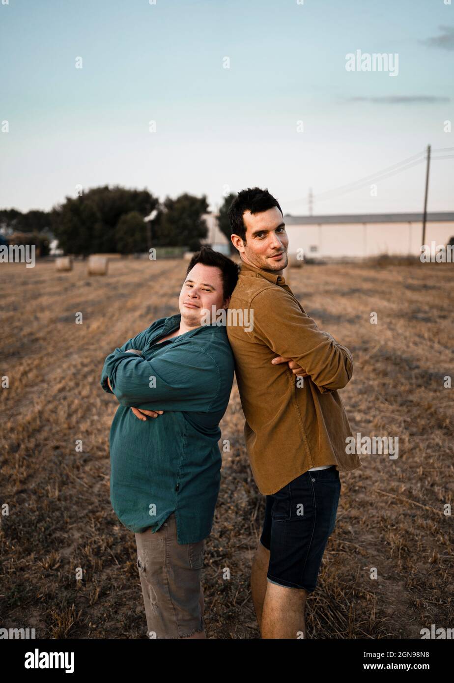 Männliche Freunde mit gekreuzten Armen stehen Rücken an Rücken Stockfoto