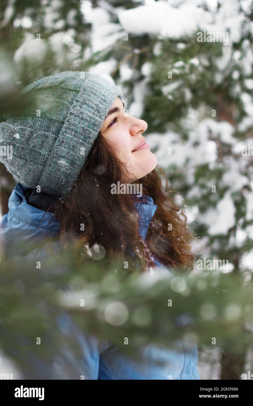 Ein Porträt einer Frau, die glücklich den fallenden Schnee bewundert, blickt auf. Stockfoto