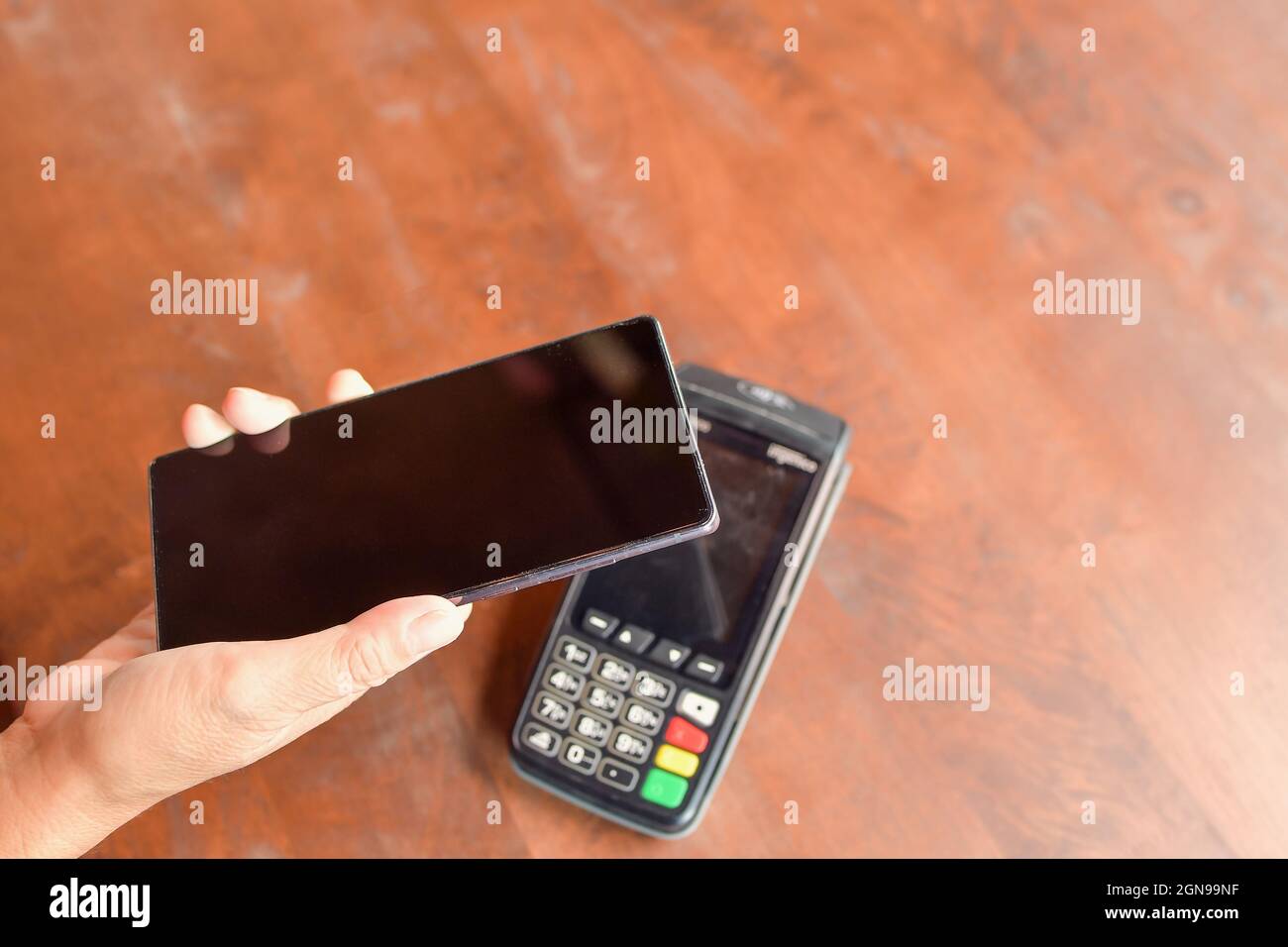 Frau, die das Smartphone in der Nähe des elektronischen Bezahlautomaten hält Stockfoto
