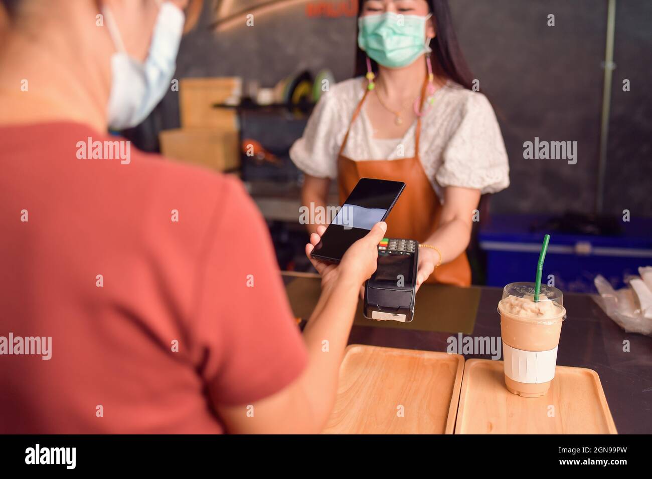 Frau, die das Smartphone in der Nähe des elektronischen Bezahlautomaten hält Stockfoto