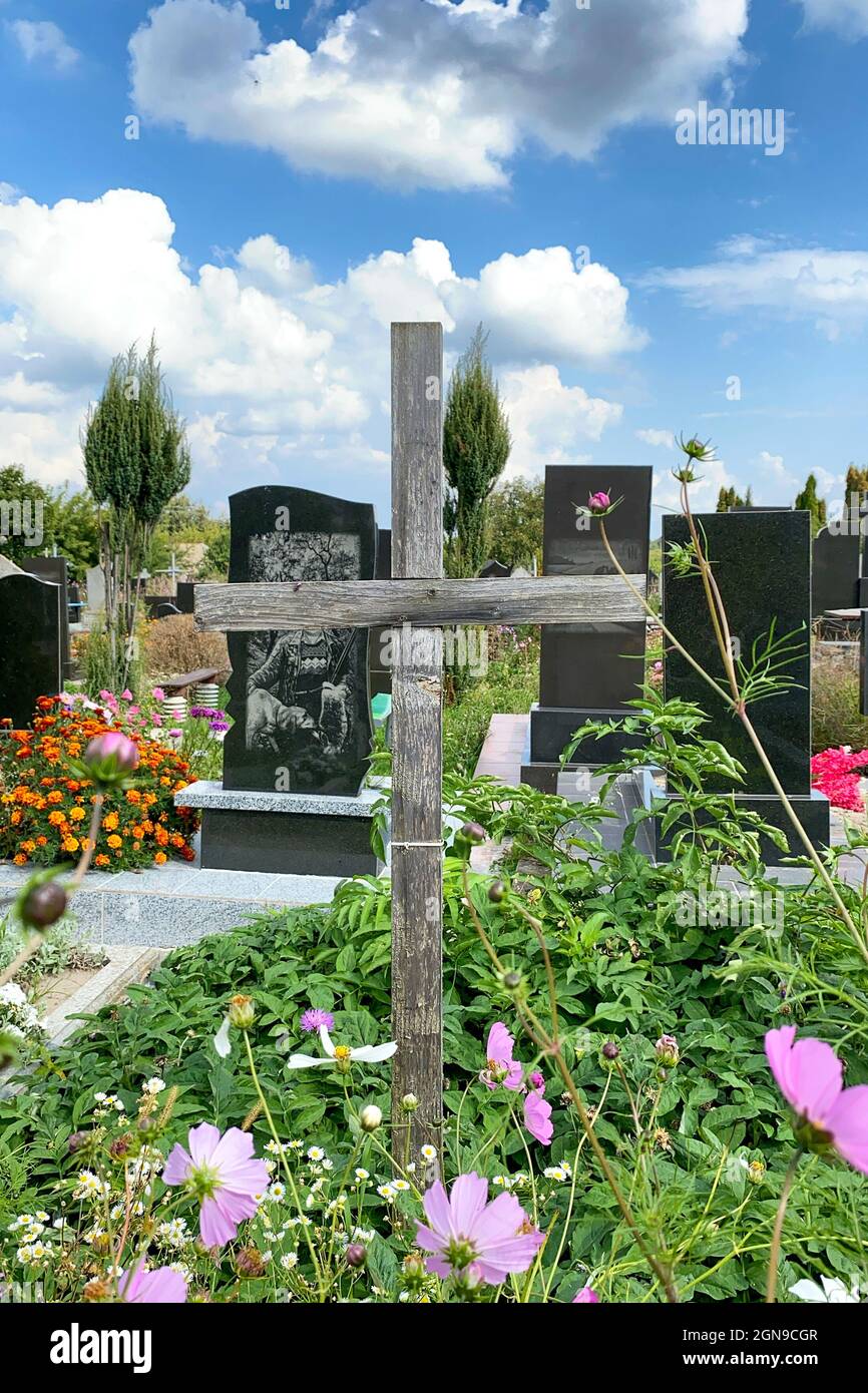 Alte holzkreuze und verschiedene Gräber auf rustikalem orthodoxen oder katholischen Friedhof. Blumen auf Grabsteinen. Mittlerer Plan. Im Freien. Stockfoto