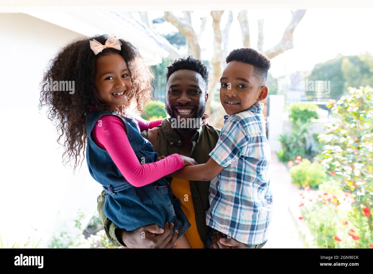 Glückliche afroamerikanische Kinder begrüßen ihren Vater, der nach Hause kommt Stockfoto