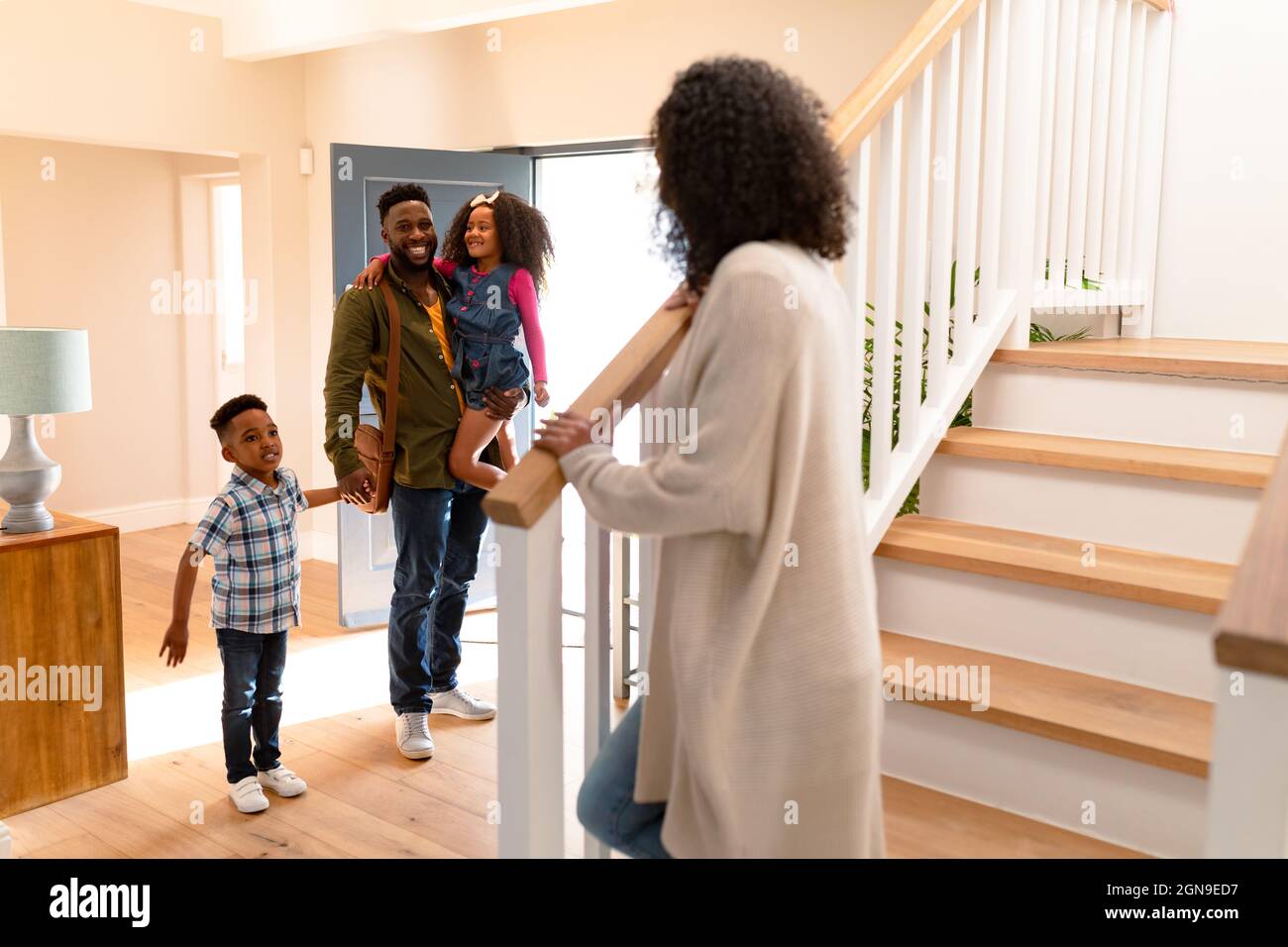 Glückliche afroamerikanische Familie, die Vater willkommen heißt, der nach Hause kommt Stockfoto Glückliche afroamerikanische Familie, die Vater willkommen heißt, der nach Hause kommt Stockfoto