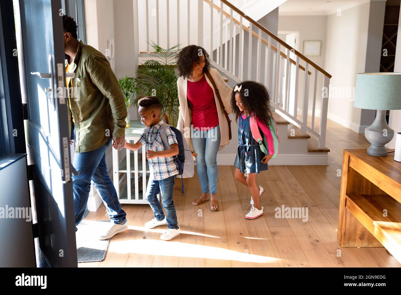 Glückliche afroamerikanische Familie, die im Flur steht, zur Schule geht und zur Arbeit geht Stockfoto