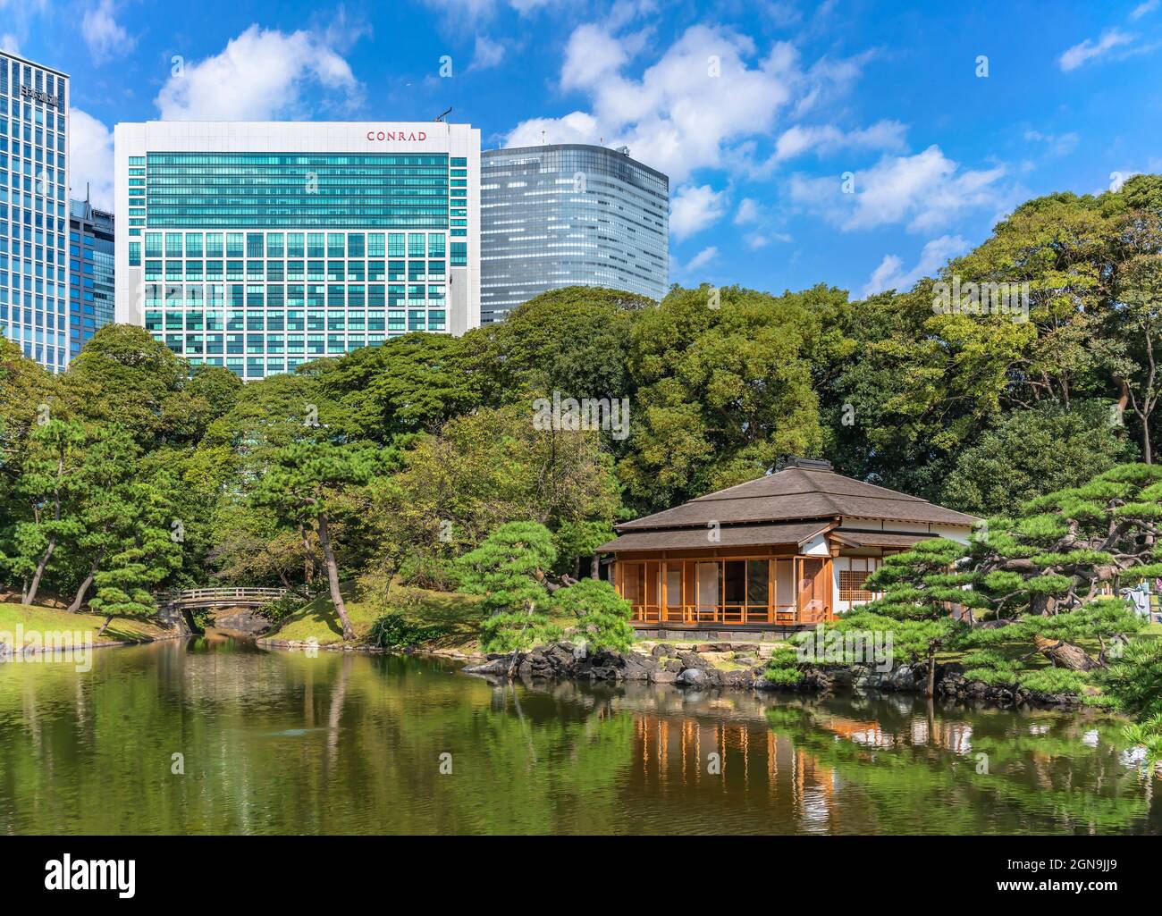 tokio, japan - oktober 28 2020: Shiori-no-ike Teich der Hama-Rikyū Gärten, die im Wasser die Gebäude und eine traditionelle japanische Chashitsu te reflektieren Stockfoto